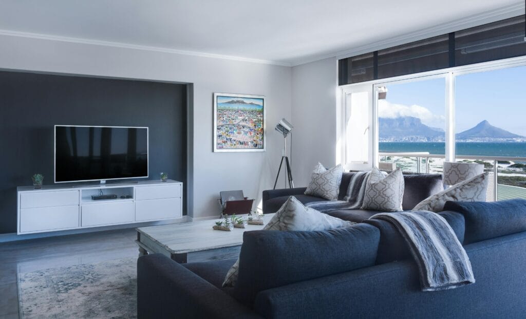 Modern living room with navy blue sofa, large windows, and ocean view